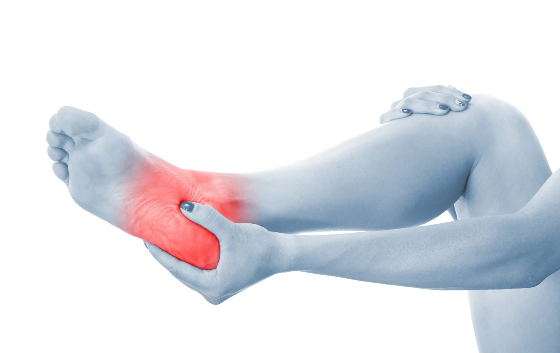 A foot and ankle held in both hands, with the painful area highlighted in red.