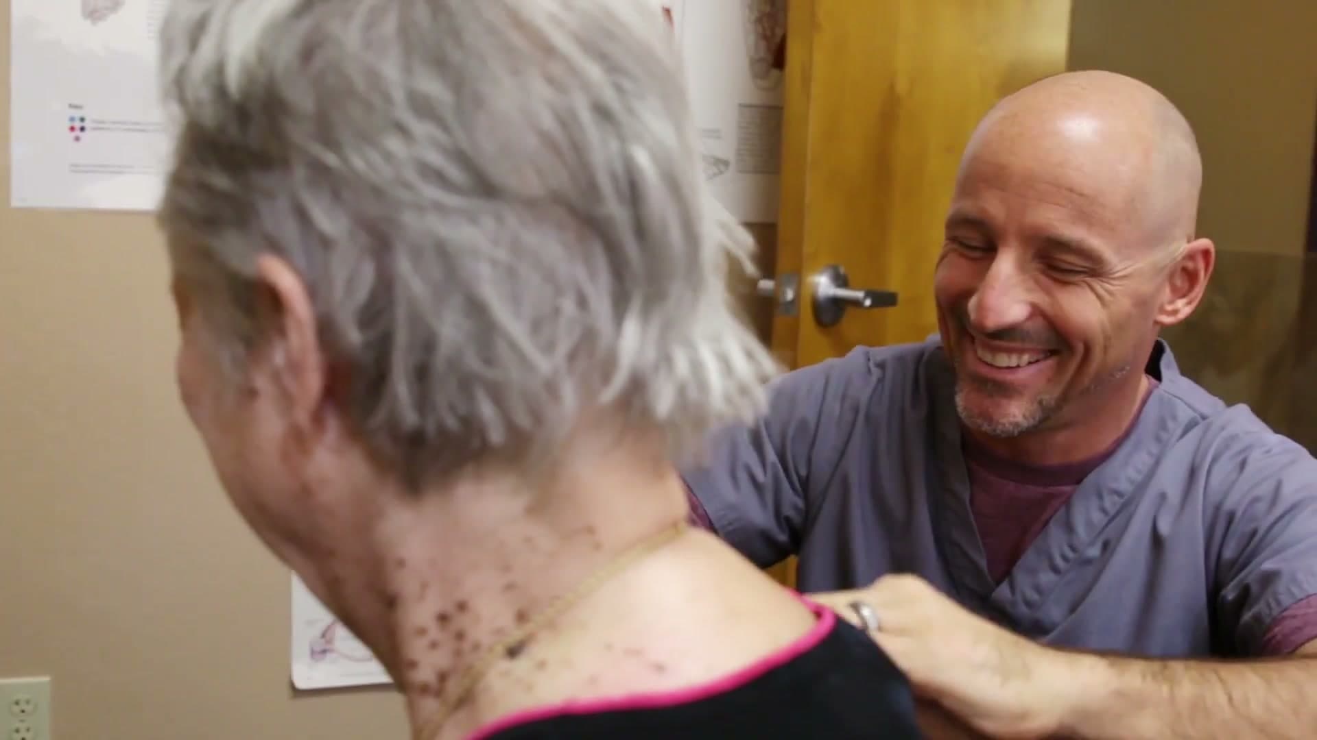 Dr. James Bogash laughing with a patient as he works on her shoulder at LifeCare Chiropractic in Mesa.